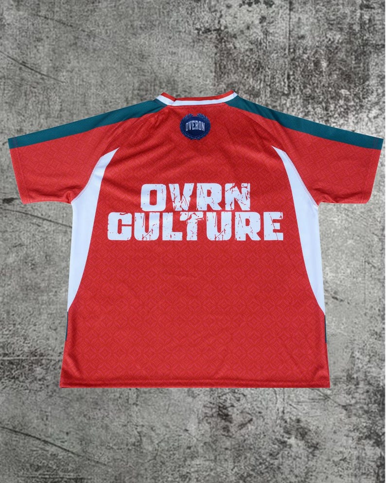 May include: A red short-sleeved jersey with dark teal shoulder panels and white side accents. The back features the white text OVRN CULTURE in a distressed font and a small circular blue patch at the neckline with the text OVERON.