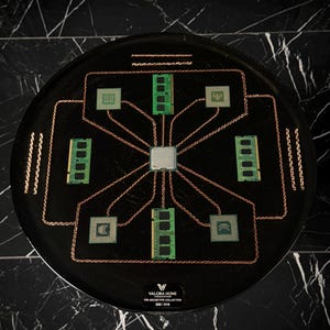 May include: A circular black display piece featuring a central silver processor chip connected by copper wires to four green RAM sticks and four square processor chips. The base includes the text VALORA HOME THE ARCHETYPE COLLECTION 200/016.