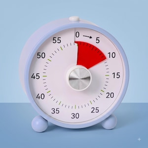 May include: A round analog visual timer with a light blue casing and two small spherical feet. The white clock face features black numerals from 0 to 55, a red segment indicating elapsed time between 0 and 10, and a central silver dial knob.