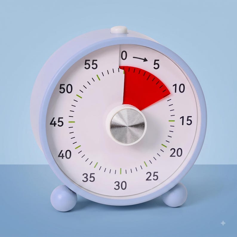 May include: A round analog visual timer with a light blue casing and two small spherical feet. The white clock face features black numerals from 0 to 55, a red segment indicating elapsed time between 0 and 10, and a central silver dial knob.