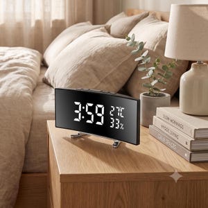 Pode incluir: Um despertador digital curvo com um ecrã preto refletor que mostra a hora 3:59 em dígitos LED brancos, juntamente com uma temperatura de 27C e 33% de humidade. O relógio apresenta um design retangular elegante suportado por dois pequenos pés prateados.