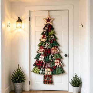 Op de afbeelding: Een stoffen kerstboom wandhanger met lagen van groene, rode en geruite stoffen ruches. De boom is versierd met kleine cadeautjes, zuurstokjes en rode bessen, en bekroond met een beige ster met een rood centrum.