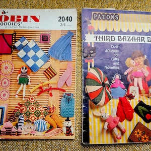 Könnte beinhalten: Zwei Strickmusterbücher. Das Buch links trägt den Titel "Robin 'Oddies' in various Robin qualities" und die Nummer 2040 auf dem Cover. Das Buch rechts trägt den Titel "Patons Third Bazaar Book" und die Nummer 156 auf dem Cover. Beide Bücher zeigen bunte gestrickte Artikel.