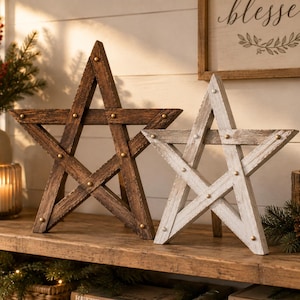 May include: Two five-pointed star decorations made of wood. One star features a dark brown stained finish, while the other has a distressed white painted finish. Both stars are constructed from joined wooden planks and feature small metal studs.