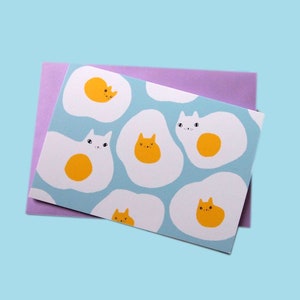 Tarjeta de felicitación en blanco ilustrada con gatos de huevo