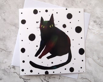 May include: A black cat with green eyes sits on a white background with black polka dots.