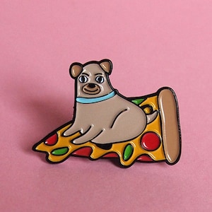May include: A brown and white dog wearing a blue collar sits on a slice of pizza with red and green toppings. The pizza slice is yellow with a brown crust. The pin is on a pink background.
