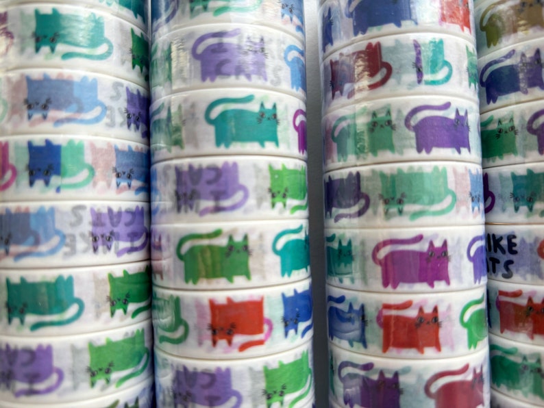 Peut inclure: Rouleaux de ruban adh&eacute;sif washi avec un motif r&eacute;p&eacute;titif de chats color&eacute;s. Les chats sont dessin&eacute;s dans un style cartoon avec diff&eacute;rentes couleurs et expressions.