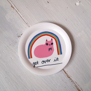 May include: White ceramic plate featuring a pink cat sitting under a rainbow with the text "get over it".