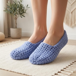 May include: A pair of light blue slip-on shoes crafted from thick, textured yarn in a crochet knit pattern. The shoes feature a rounded toe design and a low-cut opening, providing a simple, slip-on style with a visible, chunky woven fabric texture.