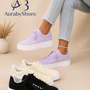 May include: A collection of platform sneakers featuring a thick white rubber sole and lace-up closure. The shoes are available in lavender, cream, and black colors. The AurabyShoes logo is visible in the upper left corner of the image.
