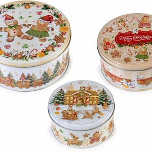 May include: Three round metal storage tins featuring Christmas themes. The largest tin shows gingerbread figures, the medium tin displays gingerbread figures with the text Merry Christmas, and the smallest tin depicts a gingerbread house and sleigh.