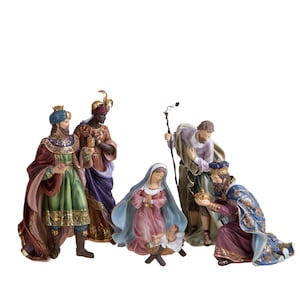 Op de afbeelding: Een kerststal-figurenset bestaande uit vijf figuren, waaronder een zuigeling in een kribbe, een knielende figuur in blauw en goud, een staande figuur met een staf, een figuur in roze en blauw, en twee staande figuren in versierde gewaden.