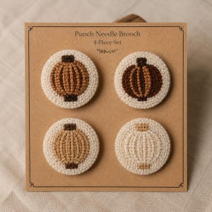 Pode incluir: Um conjunto de 4 broches de punch needle num cartão retangular castanho com a etiqueta Punch Needle Brooch 4-Piece Set. Cada broche circular apresenta um design de lanterna diferente em tons de castanho, bege e creme, com costura de fio texturizado.