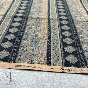 May include: A fabric featuring vertical stripes with alternating patterns of black diamond shapes, intricate floral motifs in muted green and beige, and thin dotted lines. The selvage edge displays the text COSMO TEXTILE CO., LTD. made in JAPAN.