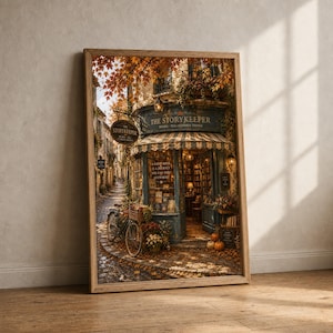 May include: A framed wall art print depicting a bookstore named The Storykeeper with a striped awning, a bicycle with a basket, and autumn foliage. The storefront features glass windows, shelves of books, and pumpkins on the cobblestone street.