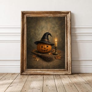 May include: A framed wall art print featuring an orange jack-o'-lantern wearing a black pointed witch hat. Beside the pumpkin sits a lit candle in a metallic holder and a wooden broomstick, all surrounded by scattered brown autumn leaves.