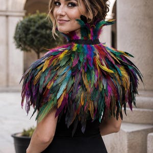 May include: A multi-colored feather collar featuring a dense arrangement of vibrant feathers in shades of green, blue, yellow, purple, and red. The collar is secured around the neck with a black band and rests over the shoulders as a capelet.