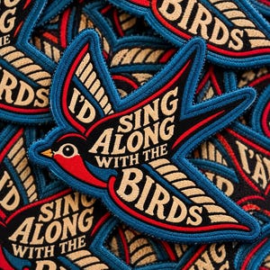 May include: An embroidered swallow-shaped patch featuring a black bird with a red throat and blue wings. The text "I'D SING ALONG WITH THE BIRDS" is stitched in tan lettering across the center of the bird's body, surrounded by blue and red borders.