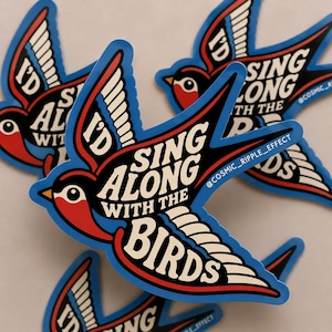 May include: A swallow-shaped sticker featuring a red, black, and white color scheme with the text I'D SING ALONG WITH THE BIRDS in bold white lettering. The design includes a blue border and the small text @COSMIC_RIPPLE_EFFECT on the wing.