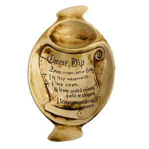 Op de afbeelding: Een keramische serveerschaal voor kaassaus met een recept voor kaassaus gedrukt op de voorkant. Het recept bevat 2 pakjes roomkaas, 1/2 eetlepel mayonaise, 1 eetlepel room, 1/4 theelepel geraspte uien, knoflook of bieslook, en 1 theelepel worcestersaus.