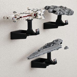 May include: Three LEGO Star Wars starship models mounted on black wall display brackets. The collection includes the white Tantive IV, the gray Millennium Falcon, and the gray Executor Super Star Destroyer, each featuring a small display plaque.