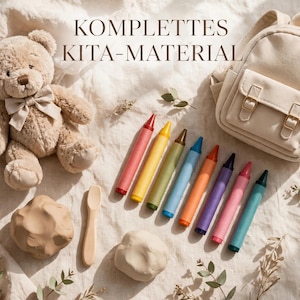 May include: A beige teddy bear with a bow, a small cream-colored backpack, eight colorful crayons, two balls of light brown modeling clay, and a wooden spoon. The text KOMPLETTES KITA-MATERIAL is visible at the top of the image.