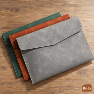 May include: Three flat document sleeves with envelope-style flaps, stacked in a staggered arrangement. The top sleeve is light gray, the middle is burnt orange, and the bottom is dark green. Each sleeve features a smooth, matte finish.