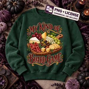 May include: A dark green crewneck sweatshirt featuring a graphic of a wooden charcuterie board with cheese, grapes, salami, crackers, and dice. The text reads "MY KIND OF BOARD GAME" in a decorative font. A "PNG + LICENSE" label is visible.