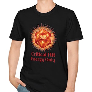 Peut inclure: Un t-shirt noir à manches courtes orné d'un motif représentant un dé à vingt faces rougeoyant avec le chiffre 20 visible sur la face avant. Sous le dé, le texte Critical Hit Energy Only est imprimé en rouge vif sur le tissu noir.