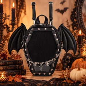 May include: A black coffin-shaped backpack featuring large bat wings on the sides, a mesh front panel, and silver-tone metal studs. A silver chain hangs across the front, adorned with small cross and skull charms, complemented by two adjustable straps.