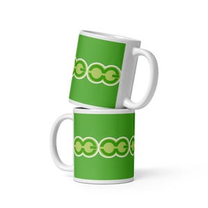 May include: Two white ceramic mugs stacked vertically, each featuring a vibrant green background decorated with a horizontal band of repeating light green and white circular chain-link patterns that wrap around the center of the cylindrical body.