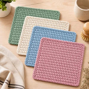 Pode incluir: Um conjunto de quatro bases para copos quadradas em croché nas cores verde sálvia, creme, azul claro e rosa antigo. Cada base apresenta um padrão de pontos densos e texturizados com uma borda uniforme, dispostas numa pilha sobreposta.