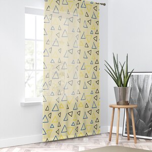 May include: A sheer curtain panel featuring a repeating pattern of hand-drawn style triangles in shades of navy blue, black, and yellow on a light cream background. The fabric is translucent, allowing light to pass through the geometric design.