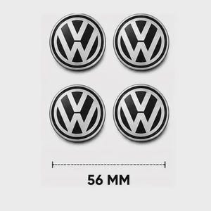 Könnte beinhalten: Ein Set aus vier runden Volkswagen Radnabendeckeln mit einem schwarz-silbernen Design und dem ikonischen VW-Logo. Eine Maßangabe unter den Emblemen zeigt deutlich einen Durchmesser von 56 mm für jedes einzelne Teil an.