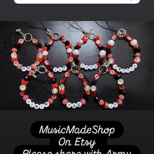 May include: Seven beaded phone charms featuring black, white, and red beads, small red bows, and white letter beads spelling RM, JIN, SUGA, J-HOPE, JIMIN, TAE, and JK. The image includes text: PLEASE SHARE WITH ARMY FRIENDS!, MusicMadeShop On Etsy, and Please share with Army.