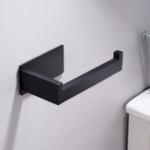May include: A matte black toilet paper holder featuring a rectangular wall-mounted base plate and a horizontal arm with a small upward-turned end piece to prevent rolls from sliding off. The design is geometric with clean, sharp edges.