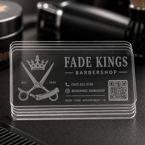May include: A stack of clear, rectangular business cards for Fade Kings Barbershop. The cards feature a white etched design including a crown, crossed scissors, a straight razor, the text Fade Kings Barbershop, a phone number, a QR code, and social media handle.