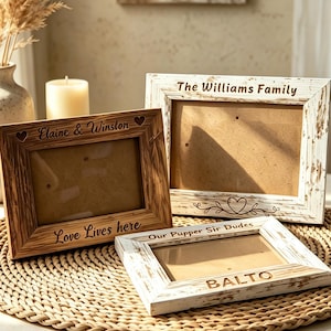 Op de afbeelding: Drie rechthoekige houten fotolijsten met een verweerde afwerking. Eén lijst is van natuurlijk hout met de inscriptie 'Elaine & Winston' en 'Love Lives here'. Twee lijsten zijn wit met 'The Williams Family' en 'Our Pupper Sir Dudes' met 'BALTO' gegraveerd.