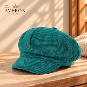 May include: A teal corduroy newsboy cap featuring a button on the top center and a structured brim. The fabric has a vertical ribbed texture. The text The AVERON HEADWEAR with a crown icon is visible in the upper left corner of the image.