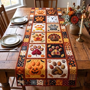 May include: A rectangular quilted table runner featuring a patchwork design of seasonal autumn and Halloween motifs. The fabric squares display appliqued paw prints filled with pumpkins, ghosts, turkeys, leaves, acorns, and candy corn patterns.