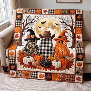 May include: A rectangular quilt featuring three ghost figures wearing hats, centered before a large full moon. The ghosts are adorned in leopard print, black and white buffalo check, and orange polka dots. Pumpkins and autumn leaves surround them.