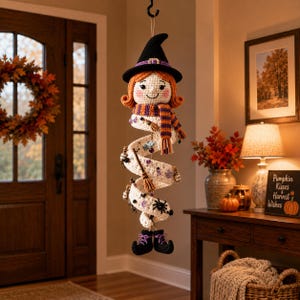 May include: A hanging crochet witch decoration featuring a spiral body, orange hair, a black pointed hat with a purple band, and a striped scarf. The white spiral body is adorned with small charms including a broom, spider, and potion bottles.