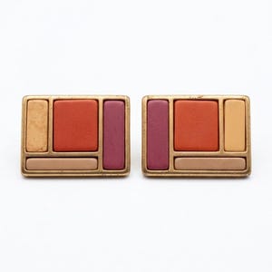 Puede incluir: Un par de pendientes rectangulares con un marco de metal dorado dividido en secciones geométricas. Cada pendiente contiene paneles mate incrustados en tonos terracota, ciruela oscuro, beige claro y un color amarillo dorado apagado.