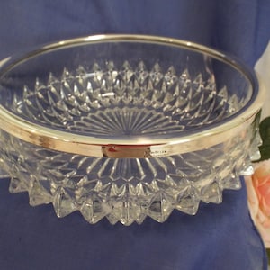 May include: A clear glass bowl with a silver rim. The bowl has a diamond pattern and is perfect for serving fruit or snacks.