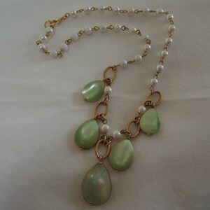 May include: A gold chain necklace with a pearl strand and green teardrop-shaped pendants.