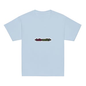 Op de afbeelding: Een lichtblauw T-shirt met korte mouwen en een centrale afbeelding met de tekst hello-world tussen zwarte punthaken. Het woord hello is roze en het woord world is limoengroen, alles op een effen lichtblauwe achtergrond.