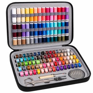 May include: A black zippered carrying case containing a large collection of multi-colored sewing thread spools, smaller bobbins, a seam ripper, metal scissors, and a circular container filled with sewing needles, all organized in dedicated slots.
