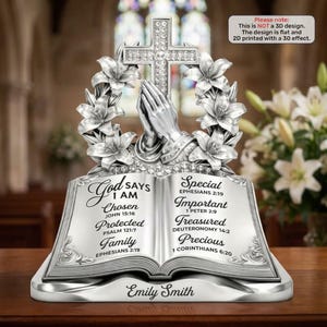 May include: A silver-toned decorative plaque featuring an open book with text, praying hands, a cross, and lilies. The text reads: God says I am Chosen, Protected, Family, Special, Important, Treasured, Precious, and the name Emily Smith.