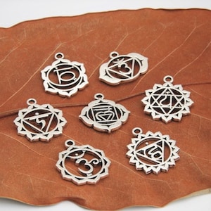 May include: Seven silver-toned metal charms with intricate designs representing the seven chakras. Each charm features a unique symbol and is surrounded by a decorative border.